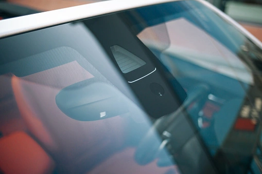 Close-up of a windshield showing the humidity sensor on windshield near the rear-view mirror in a modern vehicle.